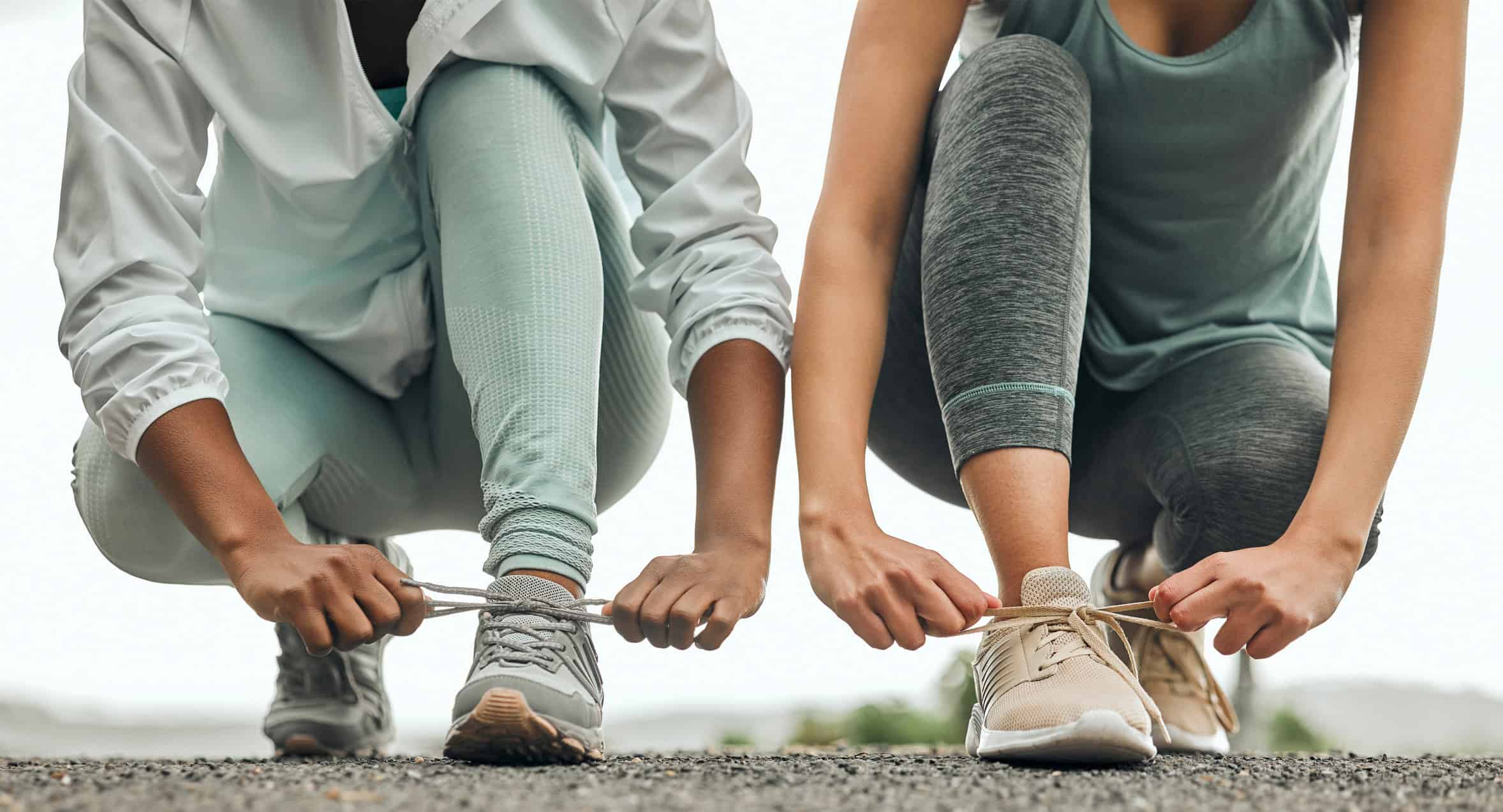 Shot of two unrecognizable people tying their shoelaces before a run