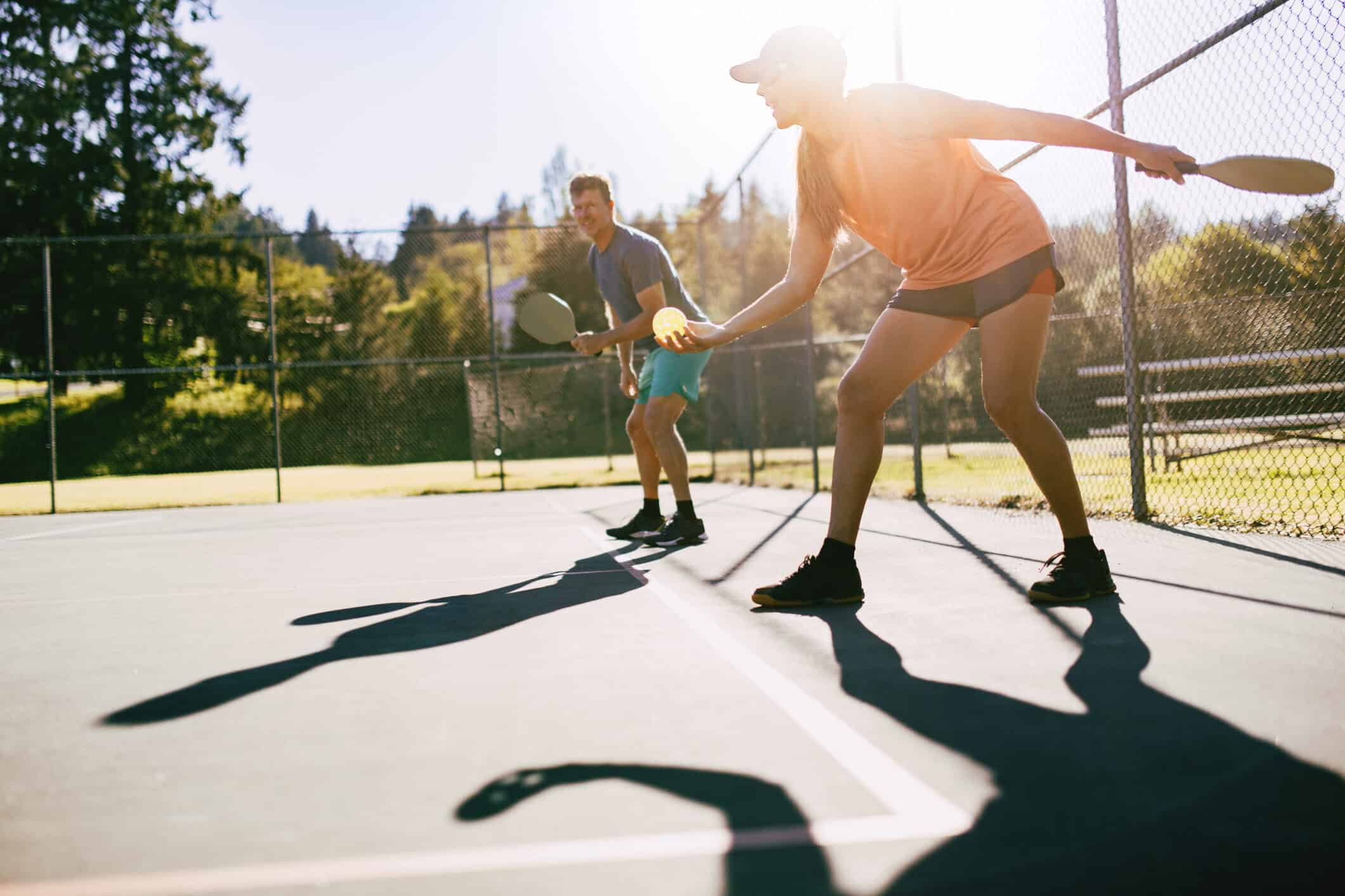 A youthful and fun Caucasian couple in their 50's enjoy the recreational sport of Pickleball on a warm day in the Pacific Northwest. Shot in Washington state.