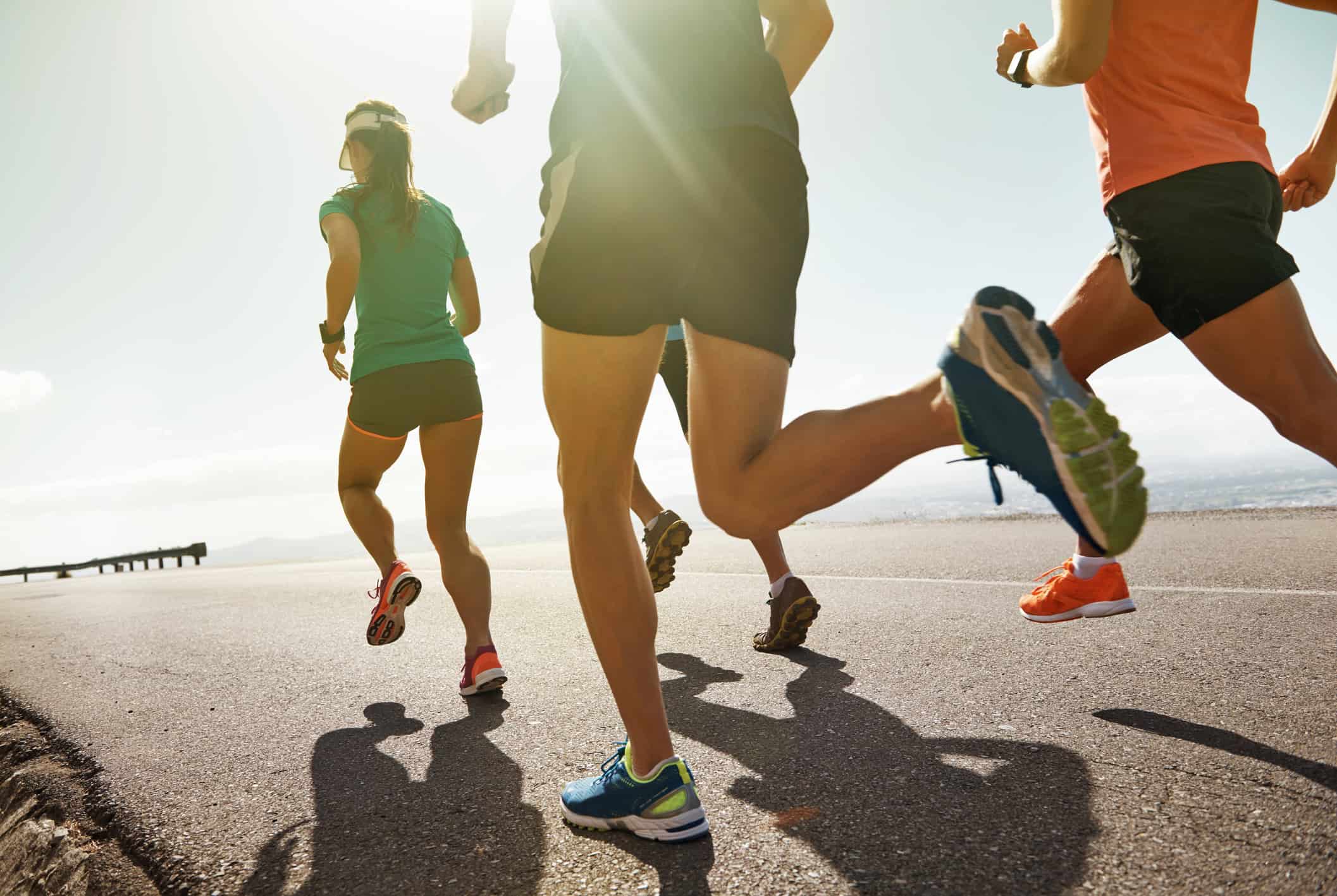 athletic group of runners jogging along a sunny road